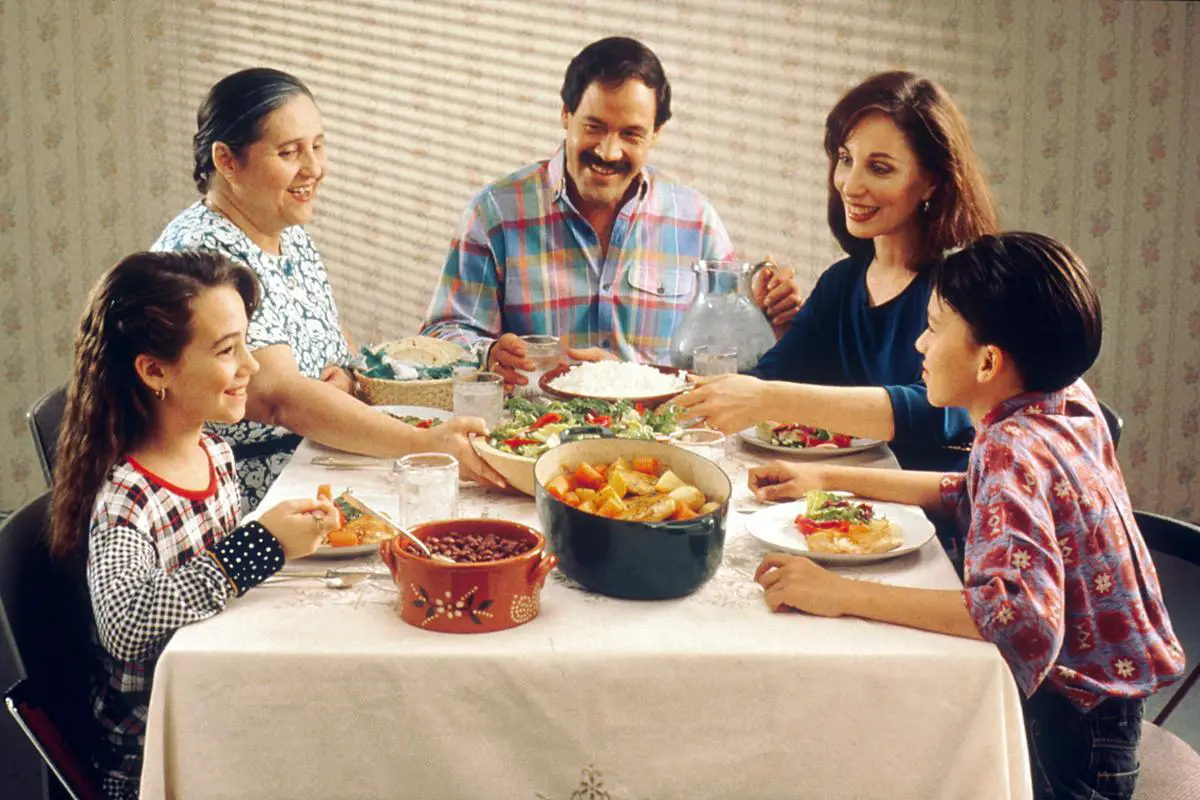 Familia española reunida alrededor de una mesa con albóndigas en salsa